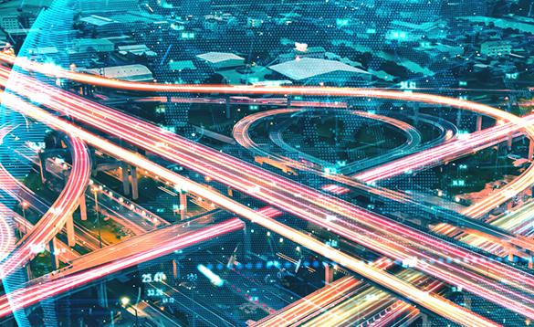 An intersection ramp with fast cars at night