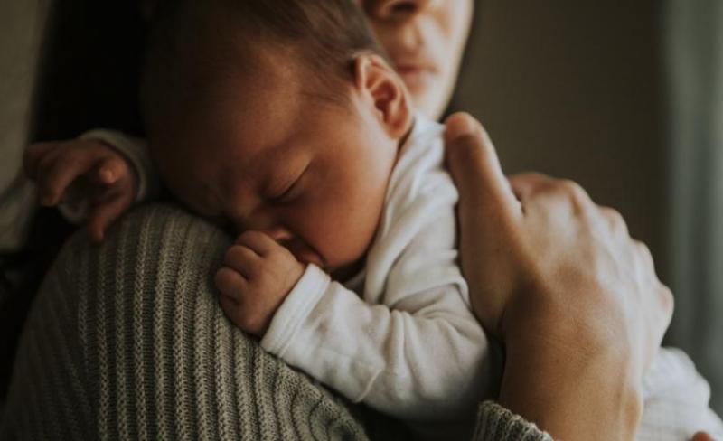 Mother holding an infant child as they sleep