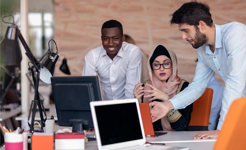 Group of employees gathered around a computer in an office