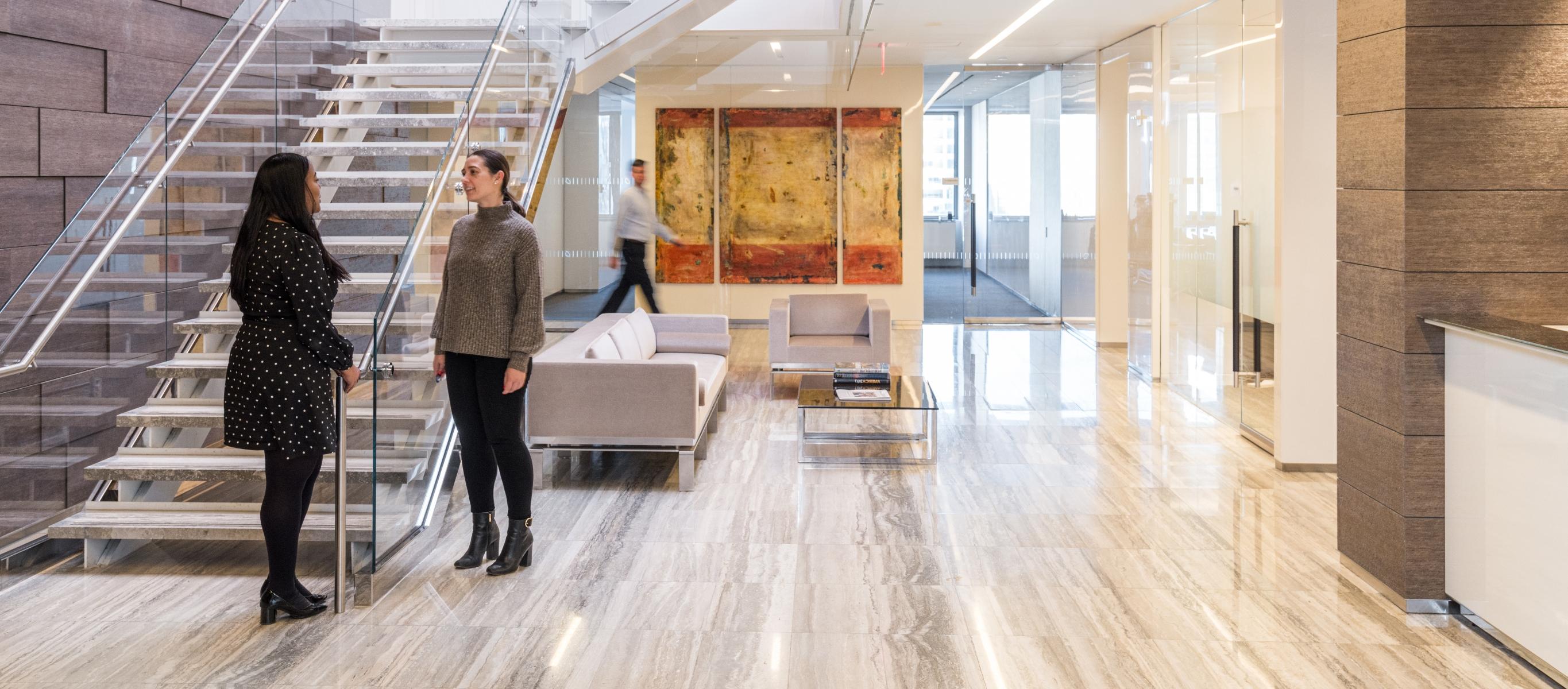 Two women talking in an Ares Management office common area 